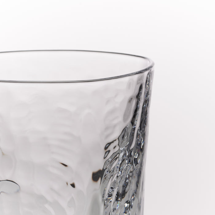 Close-up of a clear textured glass tumbler on a plain white background.