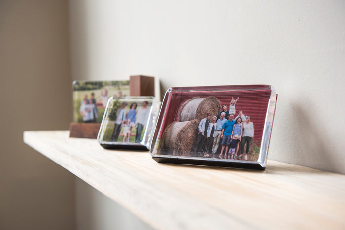 Horizontal wooden photo blocks displaying family photos arranged on a white shelf.