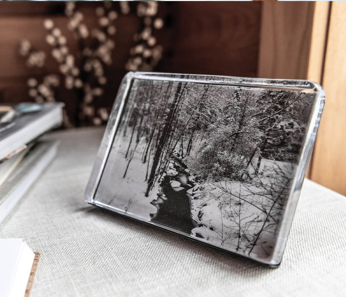Clear acrylic photo block displaying black and white forest stream landscape image in horizontal orientation.
