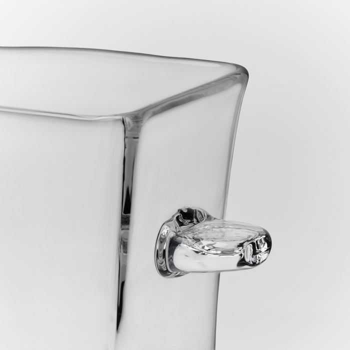 Clear glass ice bucket with curved rim and chrome-plated handle against white background.