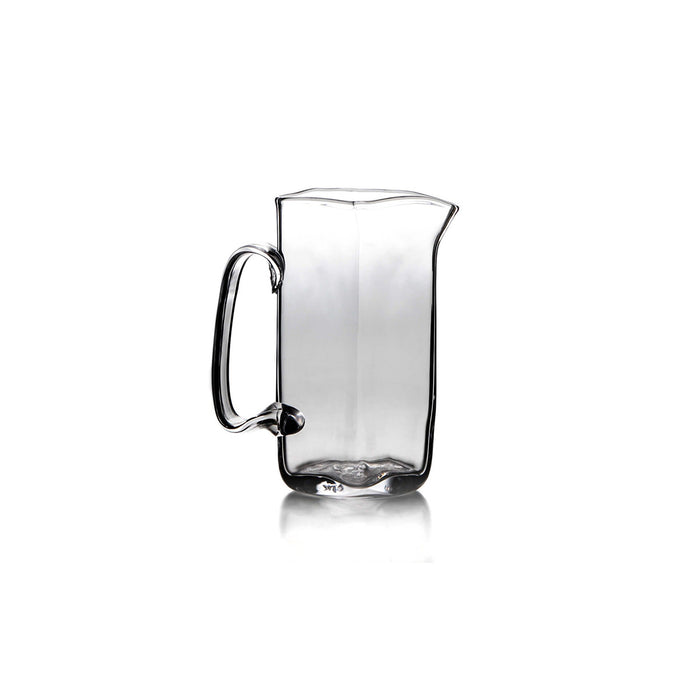 Clear glass pitcher with curved handle and tapered pouring spout.