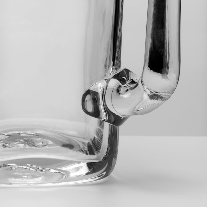 Clear glass pitcher with a handle and wide mouth, shown at an angle against a white background.