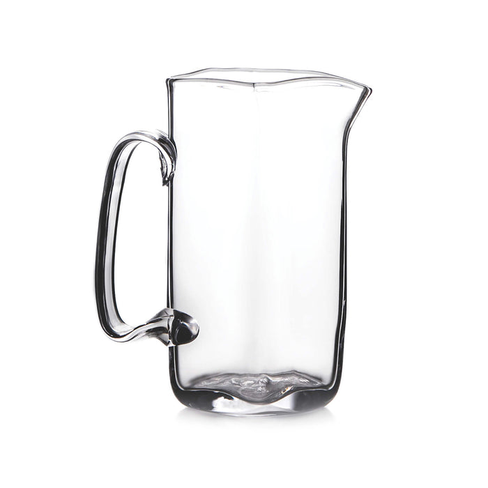 Clear glass pitcher with curved sides, wavy rim, and looped handle on left side.