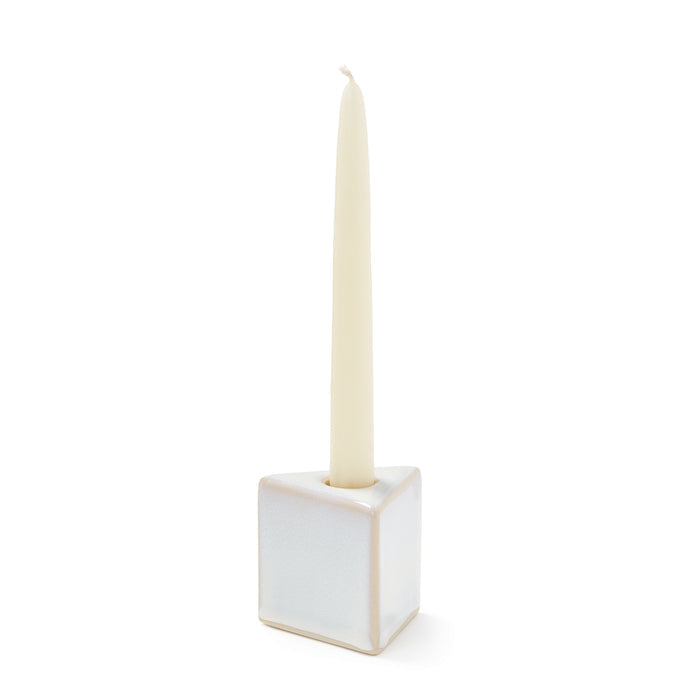 Cream taper candle in white ceramic cube holder with tapered socket.