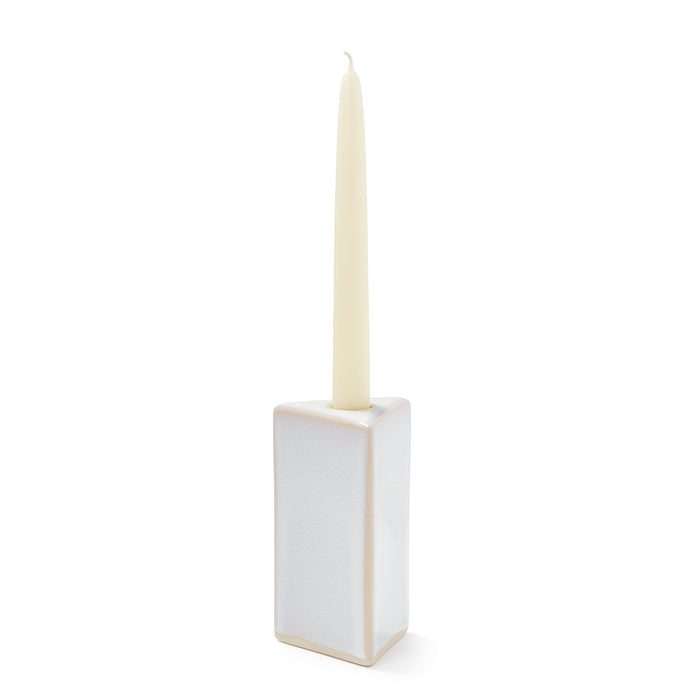 Cream-colored pottery taper candle holder with rectangular base and centered socket, holding a tapered candle.