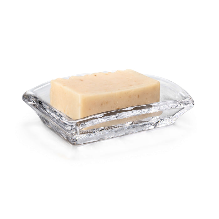 Clear glass soap dish with rectangular shape holding a beige bar of soap with visible texture.