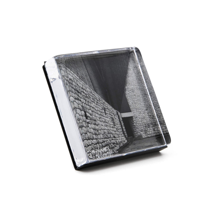 Clear acrylic photo block with white edge and black stand, displaying black and white architectural photograph of brick build