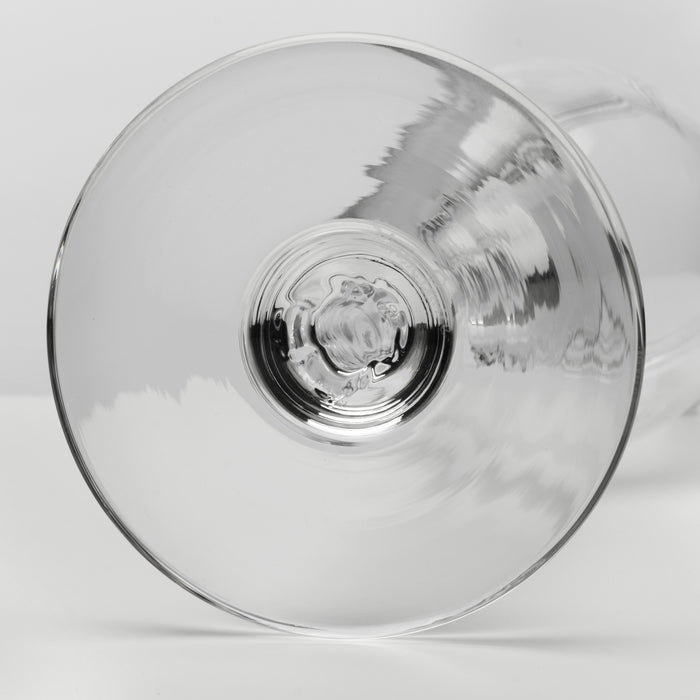 A clear glass wine glass viewed from the bottom, showing the circular bowl and a small portion of the stem against a light gray background.
