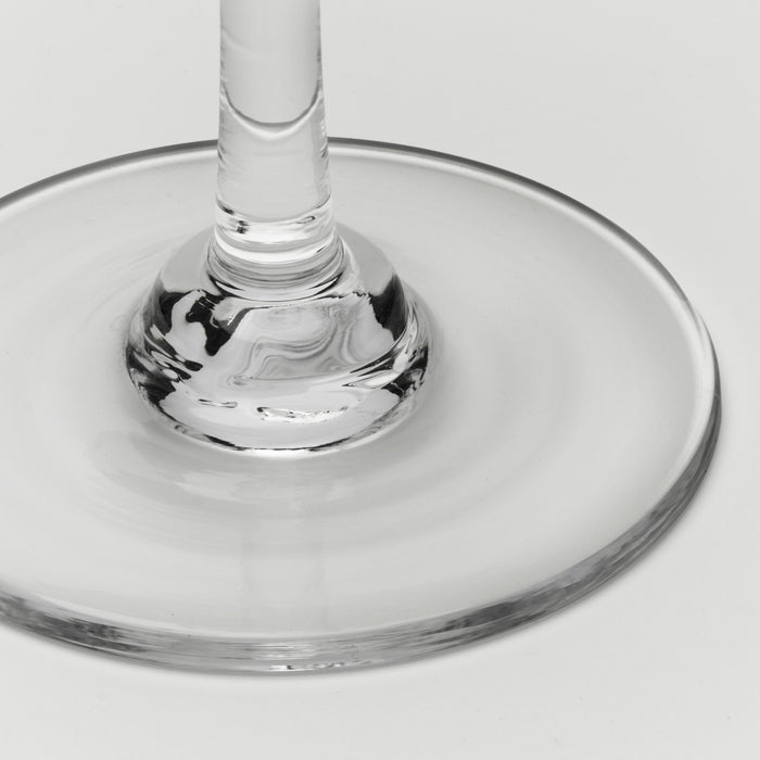 Close-up of a clear glass wine glass base and stem on a light gray background.
