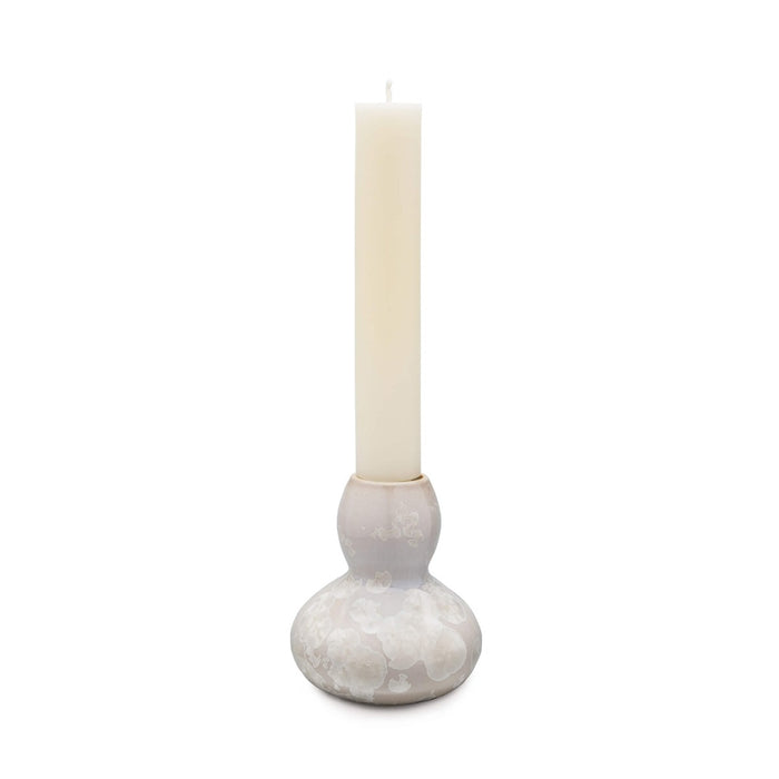 Cream pillar candle in gray and white pottery candlestick with textured spherical base.