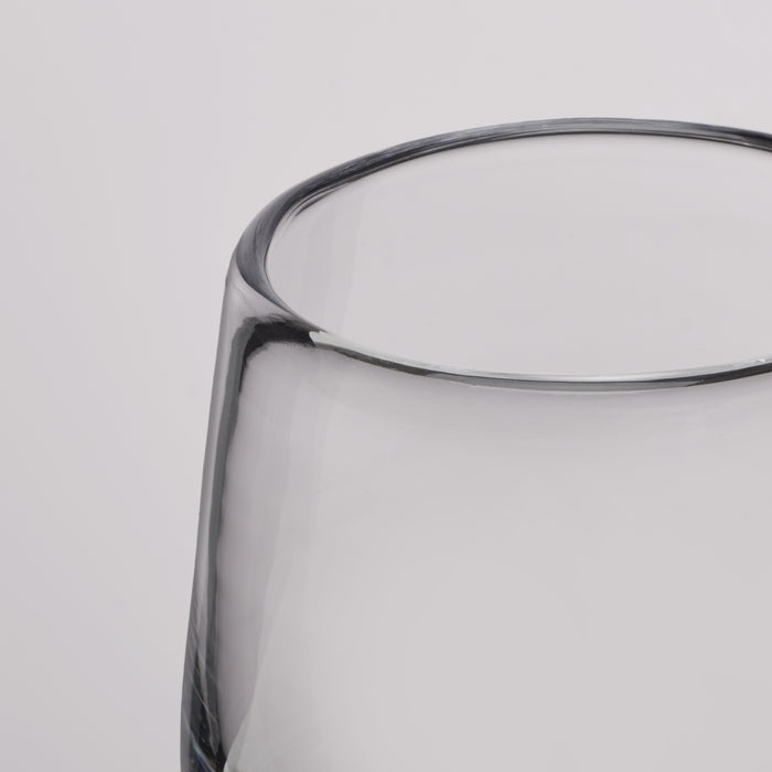 Close-up of a clear glass tumbler with a thick, rounded rim on a light gray background.