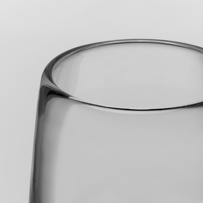 Close-up of a clear glass with a thick, rounded rim on a light gray background.